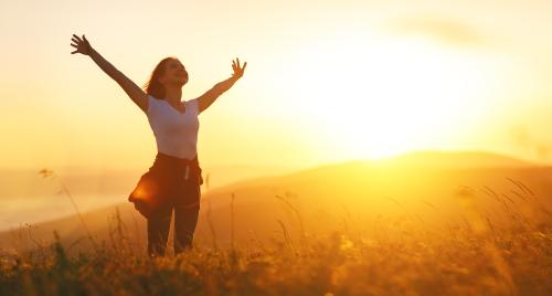 Woman with arms outstretched at sunset