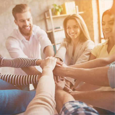 Small team gathered together placing hands together