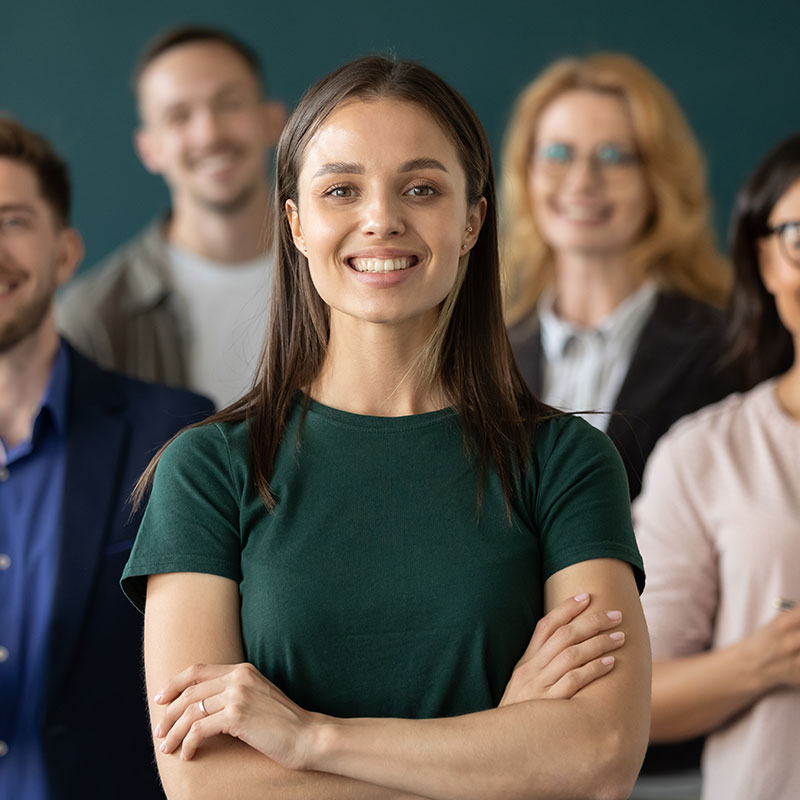 Young professional lady arms crossed with colleagues behind her