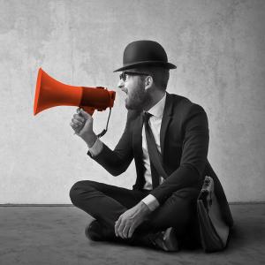 Man in black and white speaking into a red megaphone