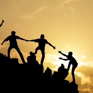 Group of hikers helping each other up a hill