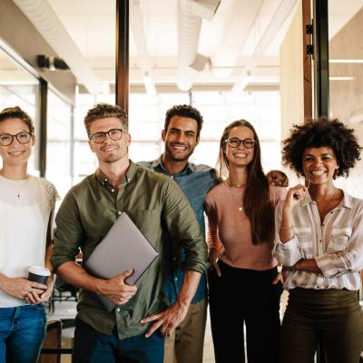 Group of smiling colleagues standing side by side in an office