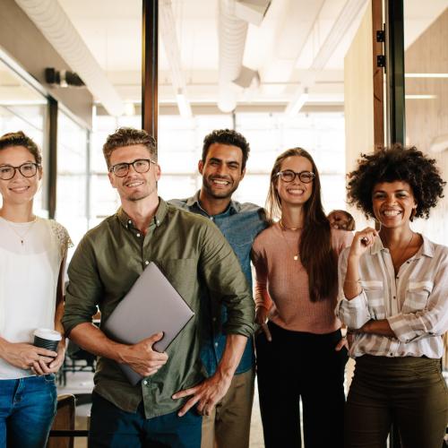 Group of smiling colleagues standing side by side in an office