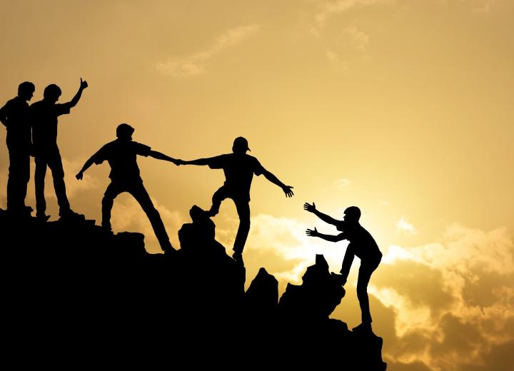 Group of people helping each other up a hill